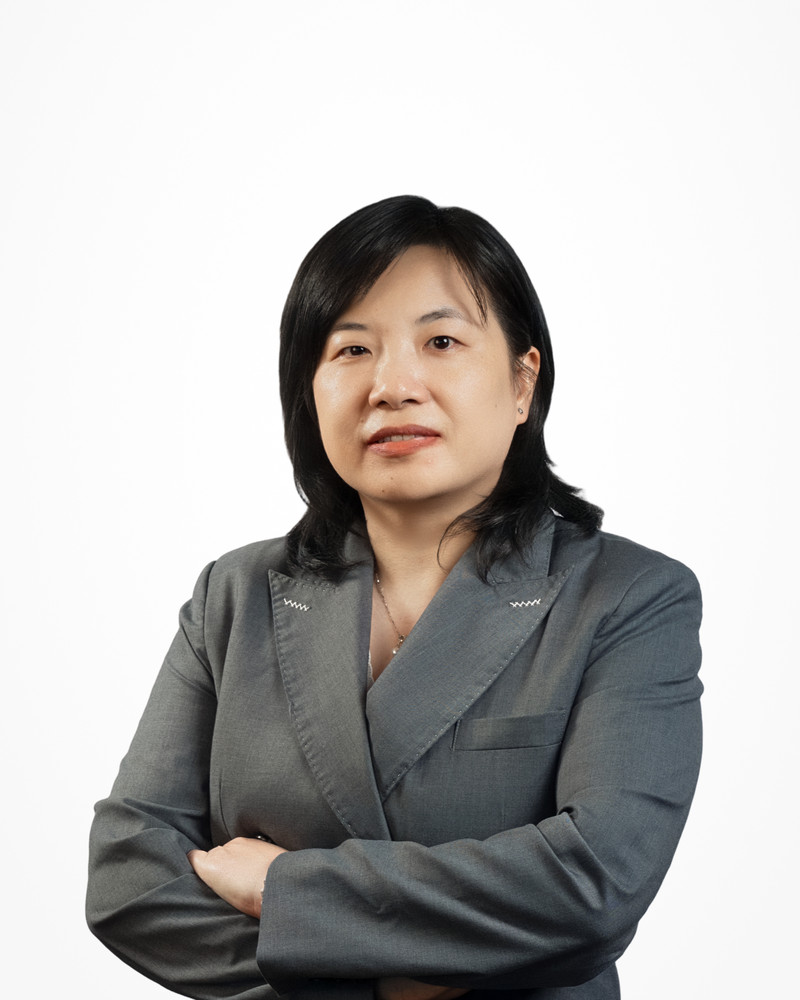 Corporate headshot of a woman in a grey suit on a white backdrop, photographed by Jay CS Films