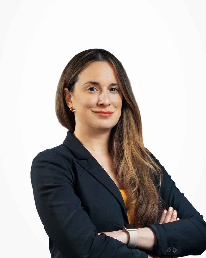 Corporate headshot of a woman with long hair in a navy blazer, arms crossed on a white backdrop, photographed by Jay CS Films