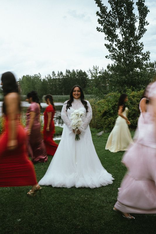 Bride holding her bouquet as bridesmaids walk past in soft focus, Montreal wedding photography