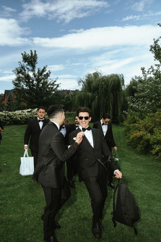 Groom in sunglasses laughing with his groomsmen on the lawn, Montreal wedding photography